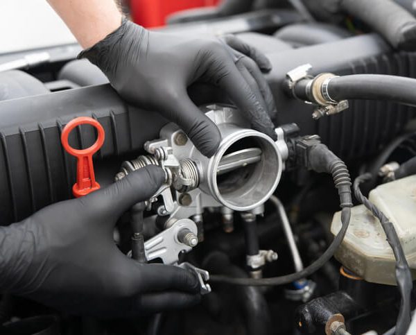 Automotive student inspecting a throttle body during engine diagnostics training