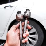 A technician checking how to know if tie rods are bad during steering inspection