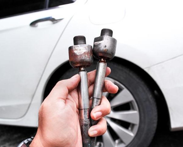 A technician checking how to know if tie rods are bad during steering inspection