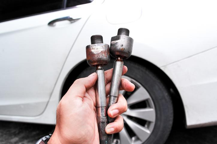 A technician checking how to know if tie rods are bad during steering inspection