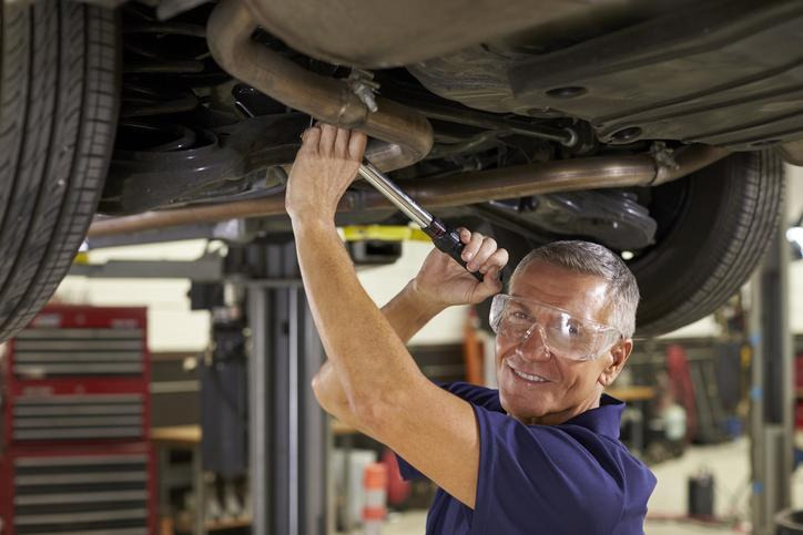 An automotive student inspecting an outer tie rod for excessive movement