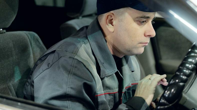A mechanic examining steering components before performing wheel alignment