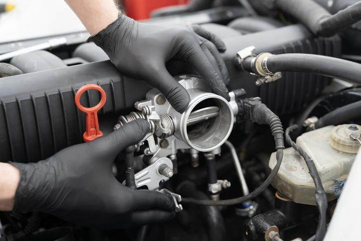 A technician inspecting a throttle body during engine diagnostics