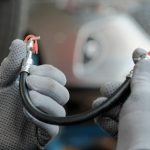 An automotive student inspecting a flexible hose for brake hose problems