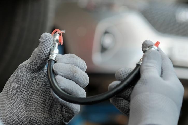 An automotive student inspecting a flexible hose for brake hose problems