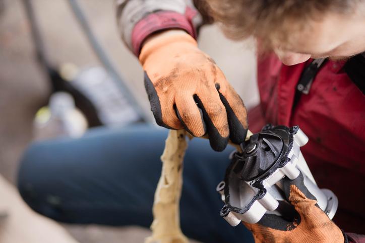 An automotive student inspecting a belt-driven water pump for bearing problems