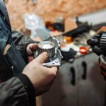 A student inspecting bad water pump symptoms in an automotive workshop