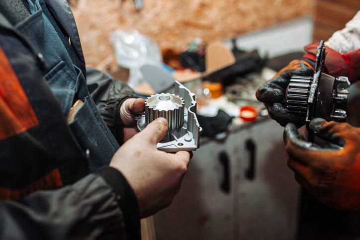 A student inspecting bad water pump symptoms in an automotive workshop